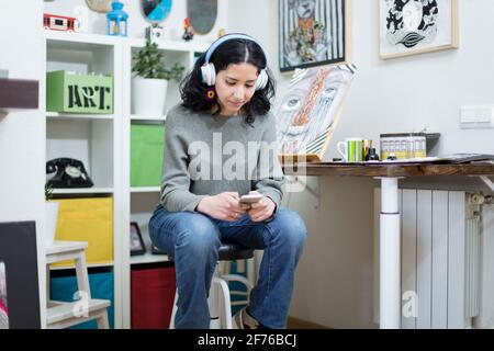 Portrait of young female art student using her mobile phone while in her studio. Space for text.