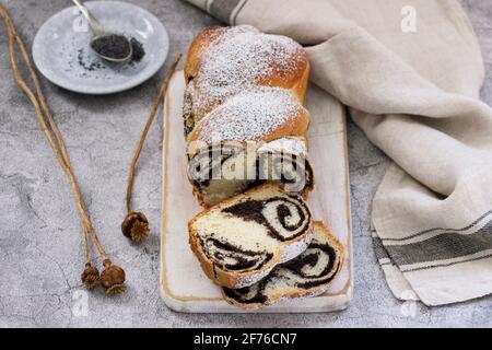 Cake with poppy filling and seed heads on a gray concrete background. Rustic style. Stock Photo