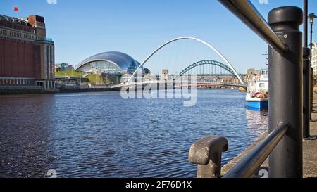 Looking through the Quayside railings up the River Tyne towards the Millennium and Tyne Bridges and Sage Centre in Newcastle-Gateshead, Tyne and Wear. Stock Photo