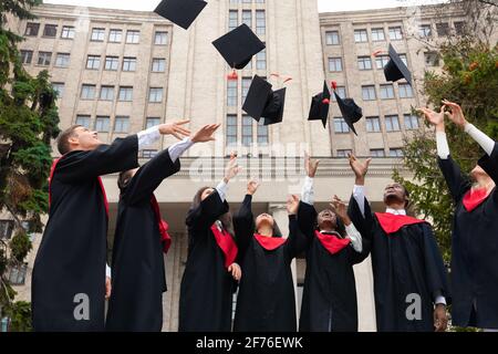 International group of students throwing graduation caps up Stock Photo