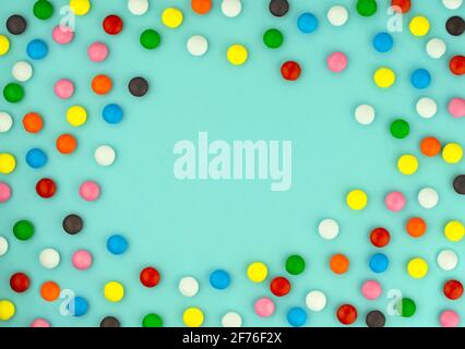 Multicolored candies frame on blue background. Chocolate sweets in colored glaze. Birthday greetings. Congratulations on holiday. Festive background f Stock Photo