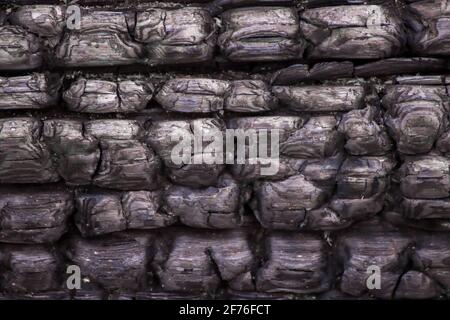 The texture of a black burnt wood surface. Rectangular coals are arranged in a line across the entire surface. Vintage background. Stock Photo