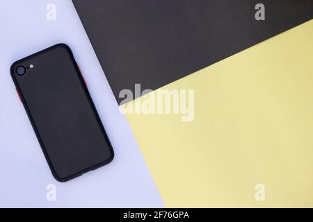A smart-phone with a blank screen mockup on multi-colored paper background. Stock Photo