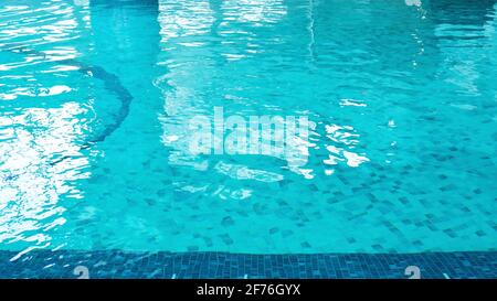 Swimming pool water surface with blue mosaic tiles. Beautiful background with texture of pool water with copy space. Nobody is in the pool. Photo coll Stock Photo
