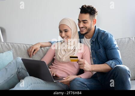 Young muslim family making purchases on Internet via laptop Stock Photo