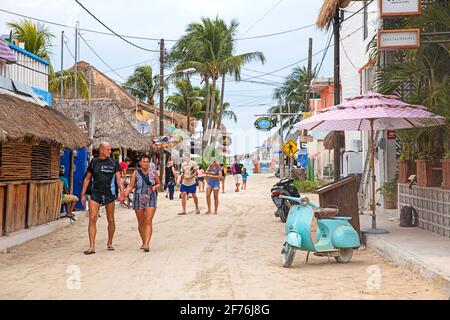 Western tourists walking in street on Isla Holbox, island in the Mexican state of Quintana Roo, along the north coast of the Yucatán Peninsula, Mexico Stock Photo