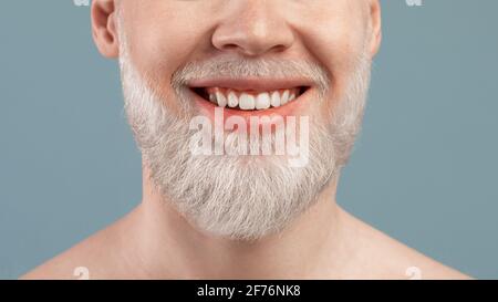Cropped portrait of albino man with wide beaming smile and healthy teeth, over turquoise studio background, closeup Stock Photo