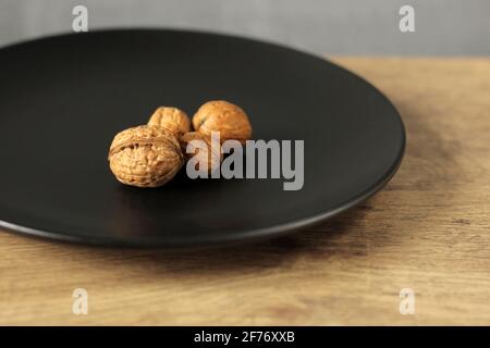 Inshell walnuts on a black plate. Healthy snack Stock Photo