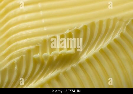 Close up of yellow butter. Full frame textured background, with a super macro perspective. Serrated butter knife used to create the abstract patterns Stock Photo