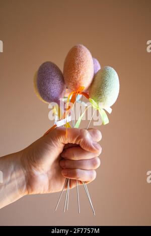 Hand holding fluffy colorful plastic eggs like a bouquet. Easter concept. Stock Photo