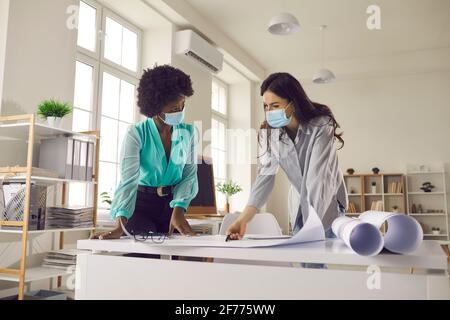 Two architects ot designers wearing face masks working on project in their office Stock Photo