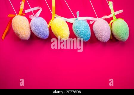Fluffy colorful plastic eggs isolated on red background. Easter concept. Copy space Stock Photo