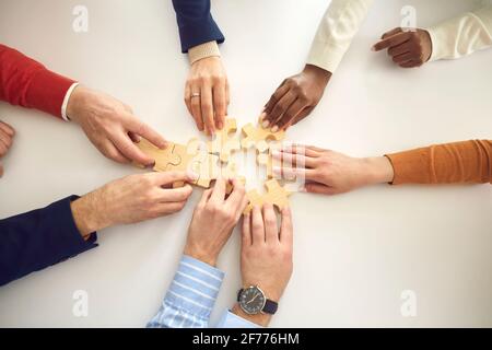 View from above of diverse business team putting together pieces of jigsaw puzzle Stock Photo