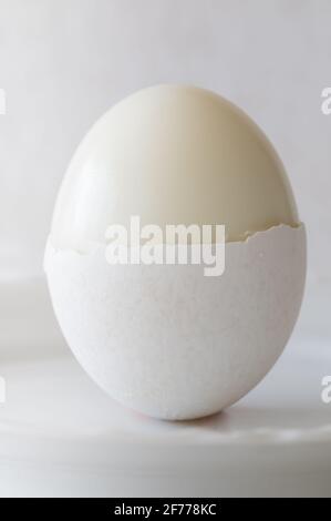 Hardboiled Egg with Half a Shell on White Background Stock Photo