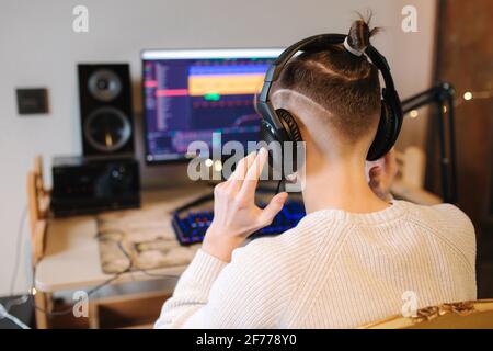 Handsome guy is recording podcast using microphone and creating content for audio blog. Man put on headphones and starting work at home. Sound Stock Photo