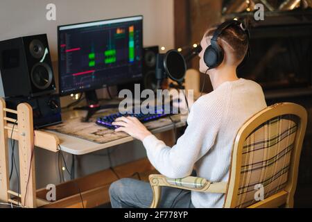 Young man in headphones makes a podcast audio recording at home. Man using pc and two professional microphones. Person recording a podcast at home Stock Photo