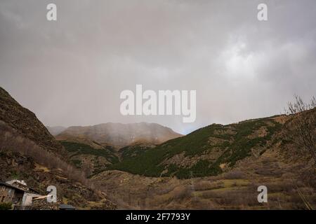 Village of Cabdella, in the Dark Valley in the Pyrenees. On an early spring day. In the background of the image, on the mountain, we can see a rain cu Stock Photo