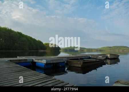 A view of a Swedish lake  with green forest in the background and a pier with boats in the foreground Stock Photo