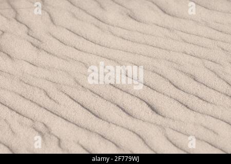 Close up shot of the patterns made by the wind in the sand by the ocean gives a summer vibe feeeling to it Stock Photo