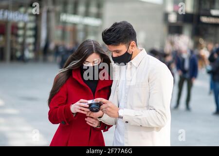 Young couple of turists taking pictures in a city during covid or coronavirus pandemic Stock Photo