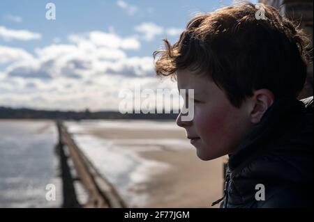 A young boy looks out to sea on Cramond Island. The island formed part of the defences during the second world war. Stock Photo