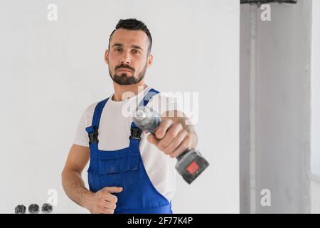 The builder looks at the camera and shows the drill Stock Photo
