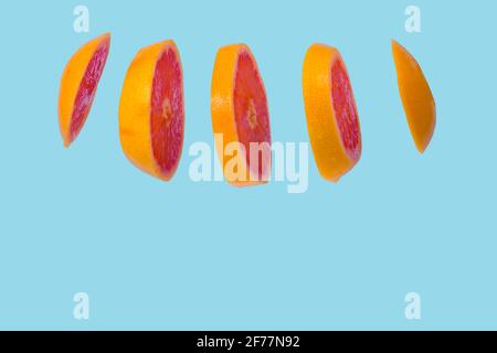 Floating levitating ripe grapefruit on bright blue background. Vitamins, healthy diet concept. Minimal fruit idea. Sliced grapefruit floating in the a Stock Photo