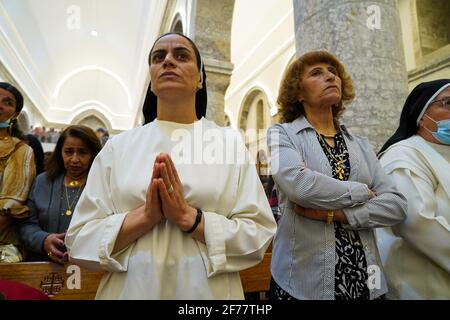 Iraqi Christians attend the Easter mass at the Grand Immaculate Church (al-Tahira-l-Kubra) in the Qaraqosh town (Al-Hamdaniya), 30 kilometers southeast of the city of Mosul.Easter is considered the greatest and largest Christian holiday, as it commemorates the resurrection of Christ from the dead after three days of his crucifixion and death, as written in the New Testament, in which the Great Lent that usually lasts forty days ends. During the liturgy the hymns are sung, parts of the Old Testament from the Bible are recited, the hymns of the Hallelujah are recited and the Gospel of the Resurr Stock Photo