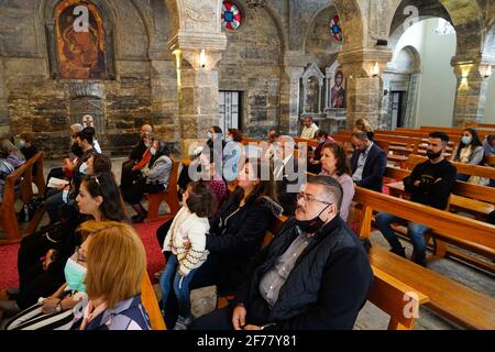 Mosul, Nineveh, Iraq. 5th Apr, 2021. Iraqi Christians attend the Easter mass at the Grand Immaculate Church (al-Tahira-l-Kubra) in the Qaraqosh town (Al-Hamdaniya), 30 kilometers southeast of the city of Mosul.Easter is considered the greatest and largest Christian holiday, as it commemorates the resurrection of Christ from the dead after three days of his crucifixion and death, as written in the New Testament, in which the Great Lent that usually lasts forty days ends. During the liturgy the hymns are sung, parts of the Old Testament from the Bible are recited, the hymns of the Hallelujah ar Stock Photo