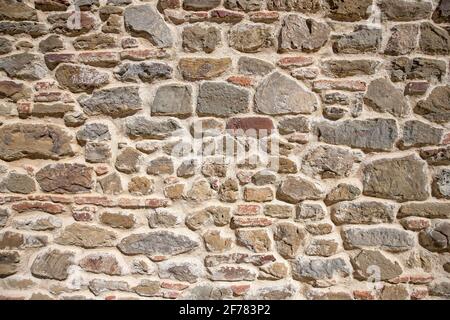 A portion of wall made of stones of different shapes and materials. Stones texture to be used as a background. Stock Photo