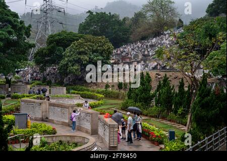 People are seen at a cemetery during the Ching Ming Festival.The annual Ching Ming Festival, when people visit the graves of deceased relatives and leave offerings in remembrance and respect as the Hong Kong government tries to keep the number of COVID-19 coronavirus infected cases under control while more people get vaccinated. Stock Photo