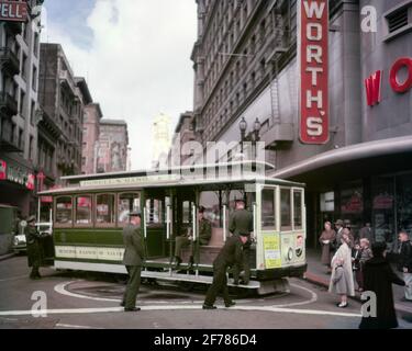 1940s 1950s GRIPMAN AND PASSENGERS AT CABLE CAR TURNAROUND ON POWELL- MASON LINE SAN FRANCISCO CALIFORNIA USA - asp c1 791 ASP001 HARS HISTORY FEMALES PASSENGERS JOBS UNITED STATES COPY SPACE LADIES PERSONS UNITED STATES OF AMERICA MALES PEDESTRIANS PROFESSION AMERICANA TRANSPORTATION FRANCISCO TURNING NORTH AMERICA SKILL OCCUPATION SKILLS WORLD'S CAREERS TOURIST LABOR MASON GRIP ATTRACTION CA EMPLOYMENT OCCUPATIONS WEST COAST CABLE CAR OPERATED EMPLOYEE GRIPMAN POWELL REVERSE TRANSIT WOOLWORTH'S CABLE LABORING LAST MANUALLY MASS TRANSIT OLD FASHIONED Stock Photo