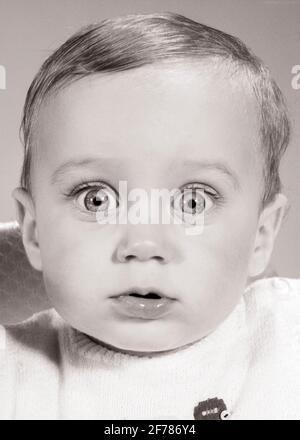 1960s WIDE-EYED BABY BOY STARING DIRECTLY AHEAD LOOKING AT CAMERA WITH SHOCKED SURPRISED FEARFUL FACIAL EXPRESSION - b22444 HAR001 HARS EXPRESSIONS AMAZED B&W WIDE EYE CONTACT WONDER BUG-EYED AWE HUMOROUS STARING HEAD AND SHOULDERS NETWORKING COMICAL DIRECTLY WONDERMENT CLOSE-UP COMEDY FEARFUL STARE AHEAD BABY BOY WIDE-EYED GROWTH JUVENILES STARTLED AMAZEMENT BLACK AND WHITE CAUCASIAN ETHNICITY HAR001 OLD FASHIONED Stock Photo