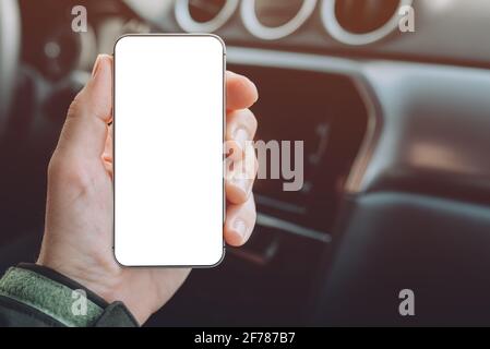 Mobile smart phone device in male hand, mock up with blank white screen. Man sitting in car and holding smartphone. Stock Photo