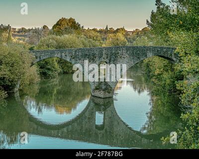 the stone bridge Puente Magdelena with two arches reflecting in the water, Rio Arga, Pamplona, Spain, October 15, 2009 Stock Photo