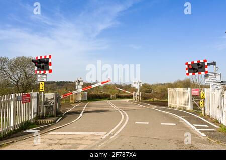Pontsarrn, near Cardiff, Wales - March 2021: Level crossing with warning lights flashing and barriers being lowered for an approaching train. Stock Photo