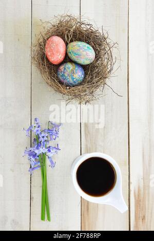 Hyacinths flowers,cup of black coffee and colored Easter eggs on wooden table Stock Photo