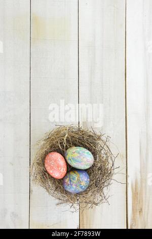 Nest with twigs and colored Easter eggs  on wooden table Stock Photo
