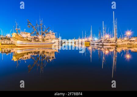 Boats reflect in water on a cloudless night at Fisherman's Terminal in the Interbay neighborhood of Seattle home to the North Pacific Fishing  Fleet Stock Photo
