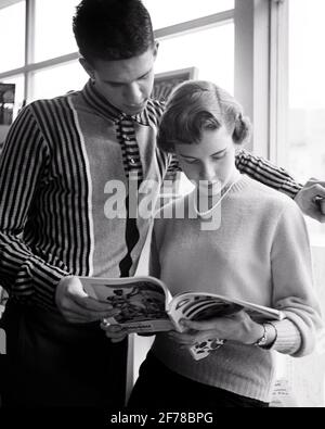 1950s TEENAGE COUPLE READING MAGAZINE BOY READING OVER THE GIRL’S SHOULDER SHE IS WEARING A SWEATER WITH SINGLE STRAND PEARLS - r11310 HAR001 HARS ROMANCE COMMUNITY SUBURBAN URBAN SHARING OLD TIME BUSY NOSTALGIA MEDIA OLD FASHION 1 PEARLS JUVENILE STYLE COMMUNICATION FRIEND TEAMWORK INFORMATION JOY LIFESTYLE SATISFACTION FEMALES COPY SPACE FRIENDSHIP HALF-LENGTH PERSONS CARING MALES TEENAGE GIRL TEENAGE BOY B&W DATING SCHOOLS UNIVERSITIES LOW ANGLE SHE HIGH SCHOOL MAGAZINES HIGH SCHOOLS HIGHER EDUCATION CONNECTION FRIENDLY STYLISH TEENAGED COLLEGES STRAND COOPERATION JUVENILES TOGETHERNESS Stock Photo