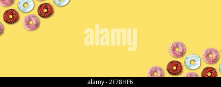 Delicious colorful donuts on yellow background, flat lay. Space for text Stock Photo