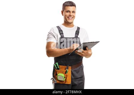 Smiling young repairman with a tool belt writing on a clipboard isolated on white background Stock Photo