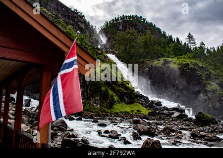 Latefossen Latefoss - one of the biggest waterfalls in Norway, with national flag on closeby building Stock Photo