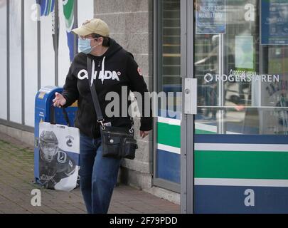 210406) -- VANCOUVER, Aprilil 6, 2021 (Xinhua) -- A resident walks past a  poster with an image of a Canucks player outside Rogers Arena in Vancouver,  British Columbia, Canada, April 5, 2021.