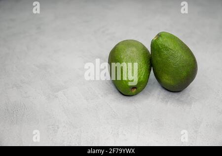 Uncut fresh ripe avocado fruit. Two whole avocado on gray background. Stock Photo