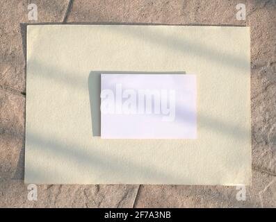 White paper or card on beige paper and rustic tiles background. Copy space. Stock Photo