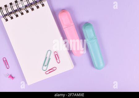 Clipboard with pink and blue text markers and paper clips on purple background with empty copy space Stock Photo