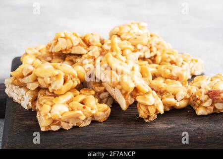 Peanuts in sugar glazed, oriental sweetness of brittle. Kozinaks are broken into pieces on a wooden Board, copy space Stock Photo