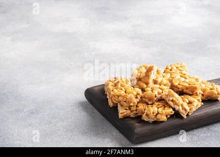 Peanuts in sugar glazed, oriental sweetness of brittle. Kozinaks are broken into pieces on a wooden Board, copy space Stock Photo