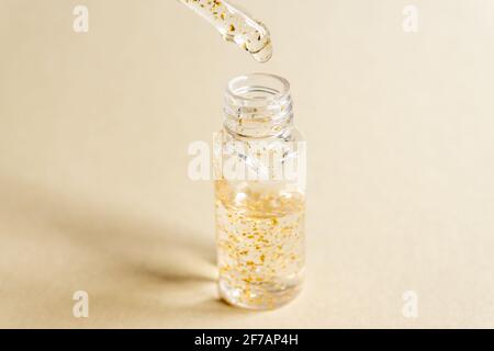 transparent bottle with beauty serum, hyaluronic acid, 24k gold and vitamins on a trayl. Home face and body care concept Stock Photo